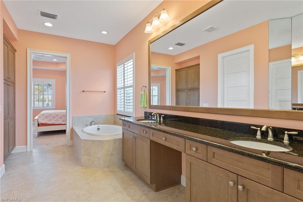 6391 Warwick Avenue Naples, FL 34113 - Photo 11 of 26 a spacious bathroom with a double vanity sink a mirror and a bathtub