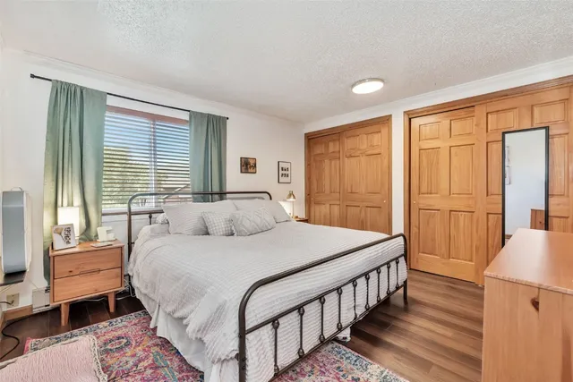 a bedroom with a bed a large window with wooden floor