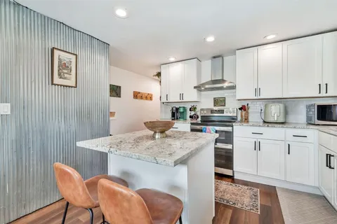 a kitchen with stainless steel appliances granite countertop a white cabinets and stove top oven