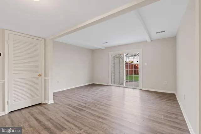 a view of an empty room with wooden floor and entryway