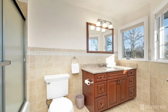 a bathroom with a granite countertop toilet sink and mirror