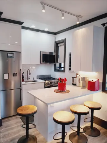 a kitchen with stainless steel appliances wooden floor and chairs