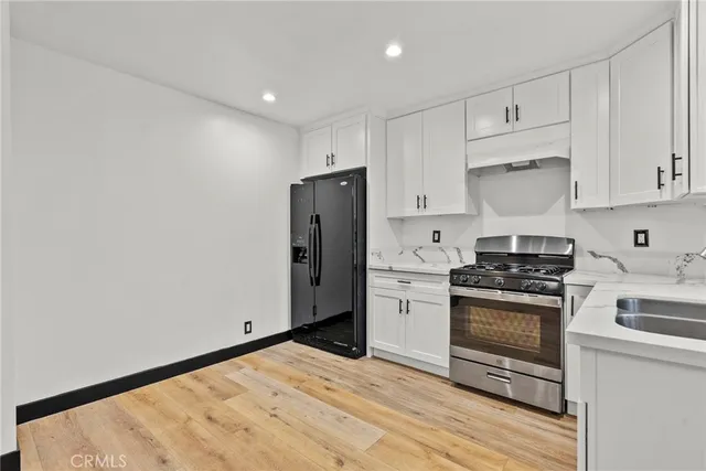a kitchen with stainless steel appliances granite countertop a stove a refrigerator and a white cabinets