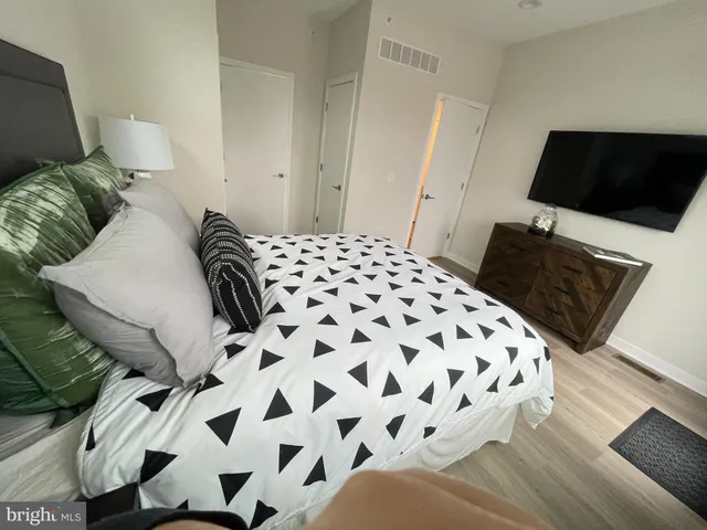 a bedroom with a bed and a flat tv screen on a dresser