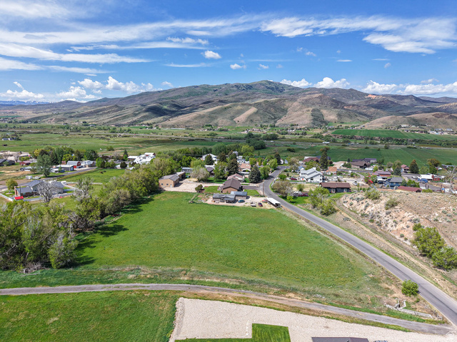 94 Spring Canyon Road Coalville, UT 84017 - Photo 16 of 50 Expansive green space featuring a paved road, mature trees, and mountainous terrain in the background
