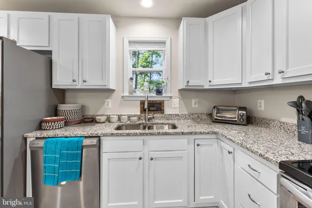 a kitchen with granite countertop white cabinets and white appliances