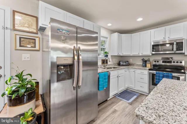 a kitchen with stainless steel appliances granite countertop a refrigerator a stove a sink a microwave and cabinets