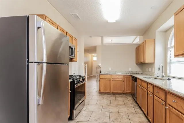 a kitchen with stainless steel appliances granite countertop a refrigerator and a sink