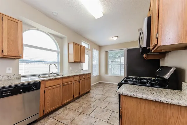 a kitchen with granite countertop a sink a stove and cabinets