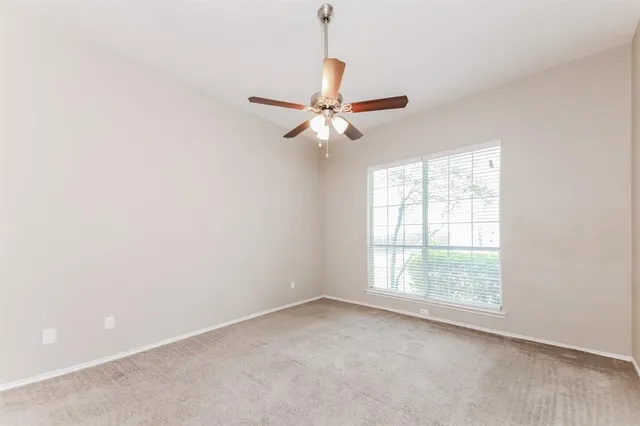 an empty room with a window and a fan