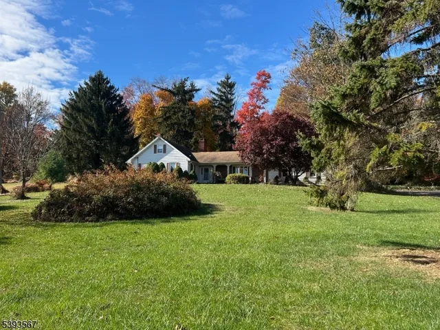 a view of a house with a big yard and large trees