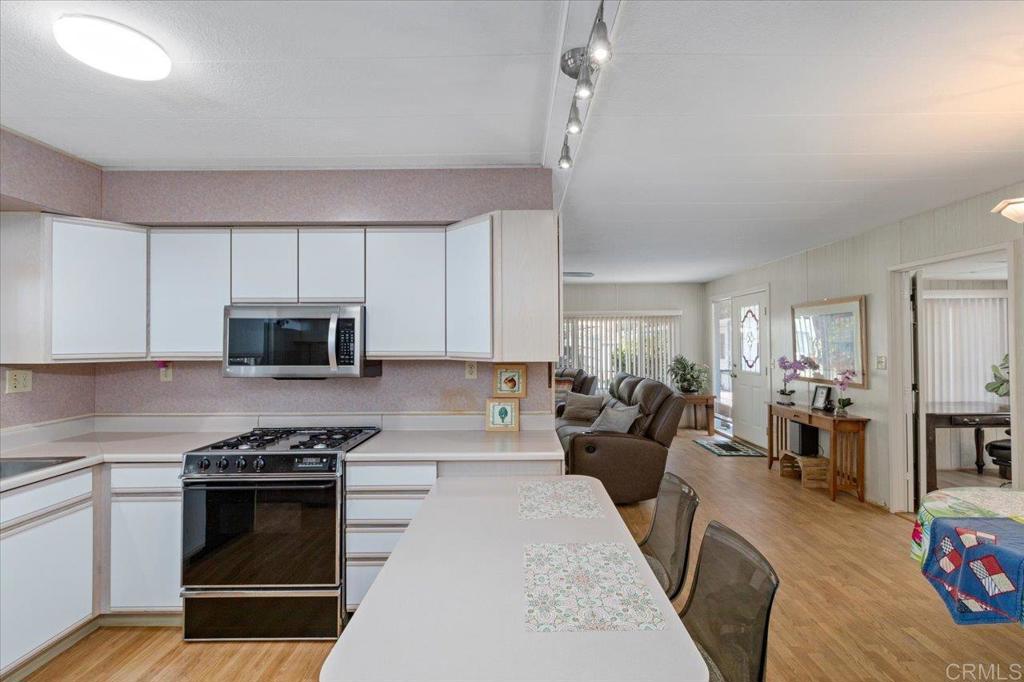 28890 Lilac Road, Unit 80 Valley Center, CA 92082 - Photo 11 of 33 a kitchen with stainless steel appliances a stove a sink dishwasher a refrigerator white cabinets and wooden floor