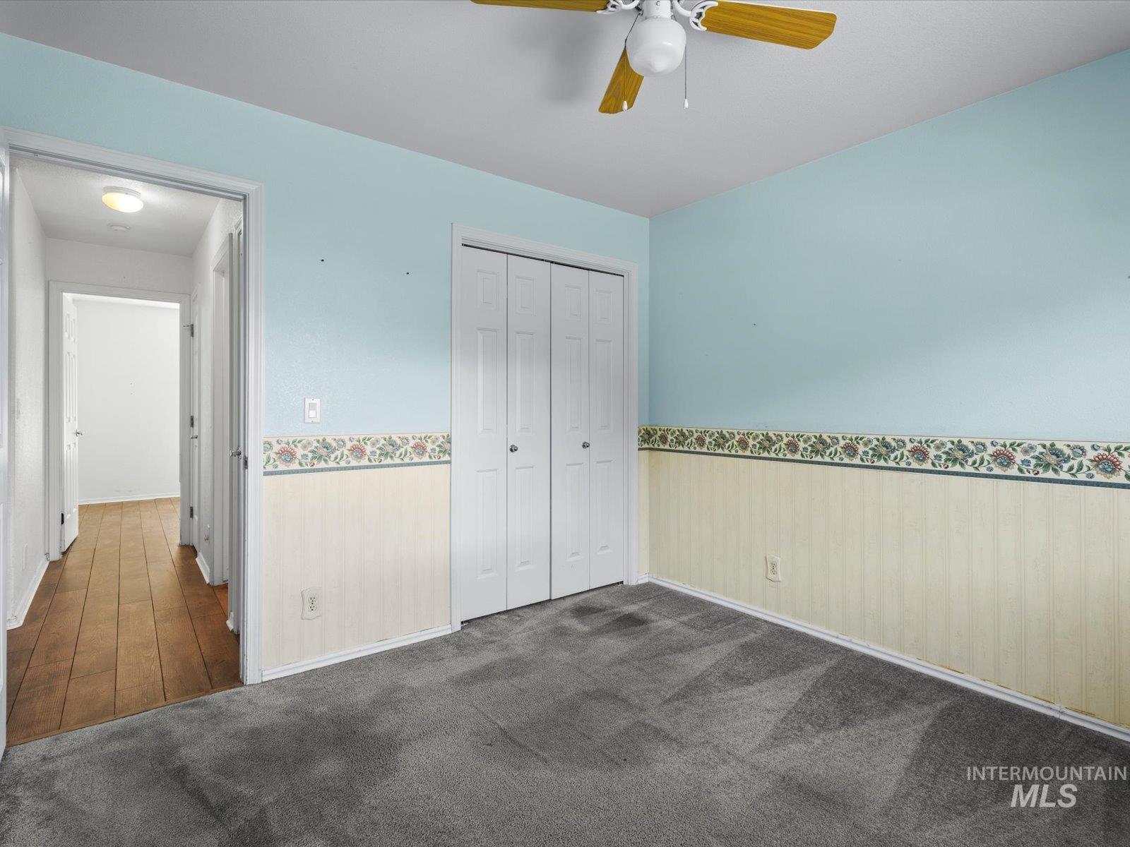 3540 Wills Road Emmett, ID 83617 - Photo 24 of 36 Carpeted room featuring light blue walls, a ceiling fan, bi-fold closet doors, and decorative wainscoting