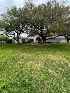 a view of a house with a big yard and large trees