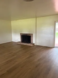 a view of empty room with wooden floor and fireplace