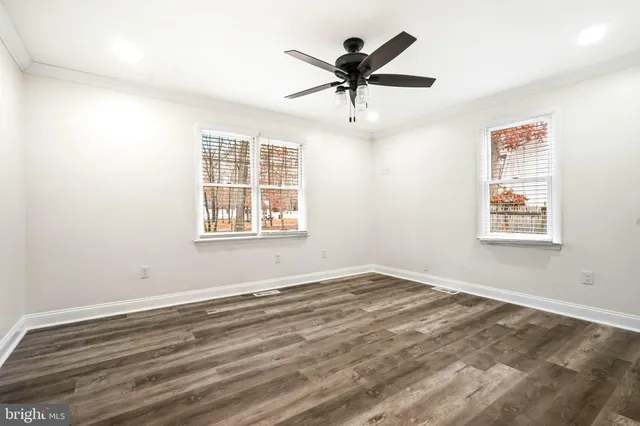 a view of a big room with wooden floor and windows