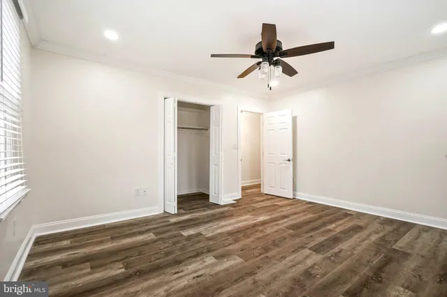 an empty room with wooden floor ceiling fan and windows