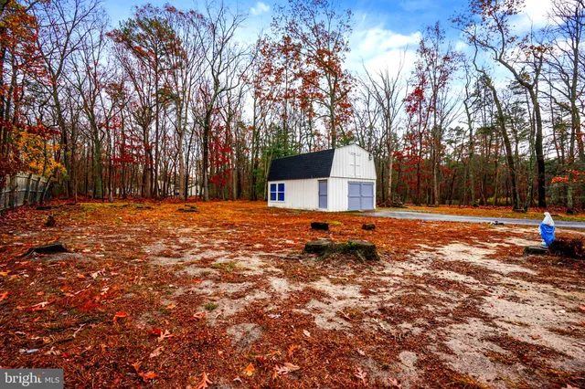 a backyard of a house with large trees and outdoor seating
