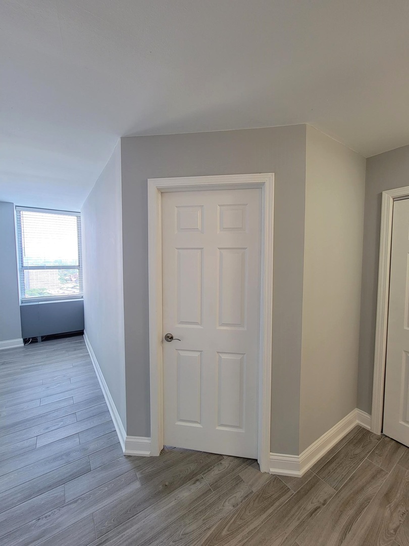 655 West Irving Park Road, Unit 2611 Chicago, IL 60613 - Photo 12 of 32 an empty room with wooden floor cabinet and windows