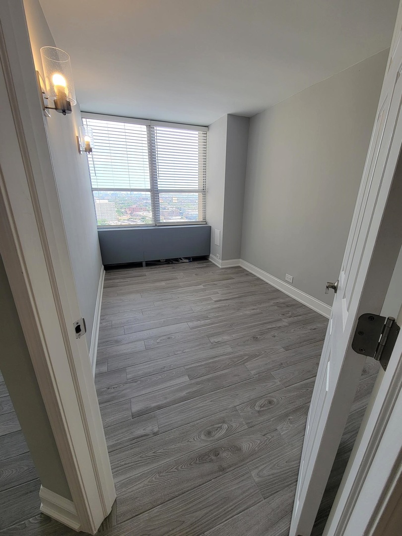 655 West Irving Park Road, Unit 2611 Chicago, IL 60613 - Photo 18 of 32 a view of an empty room with a window and wooden floor