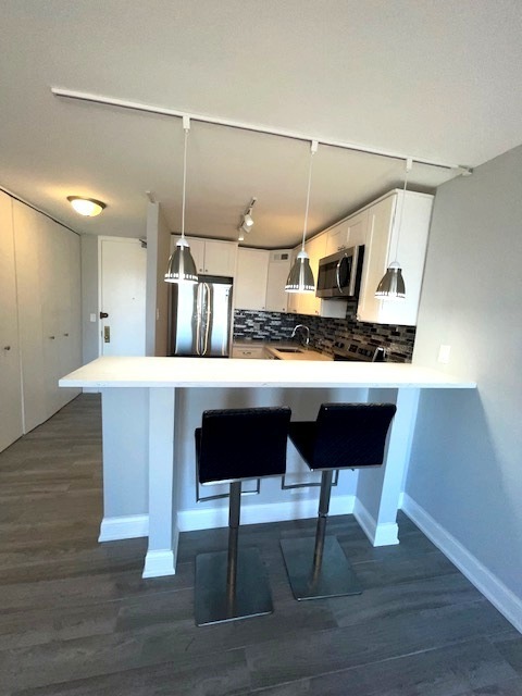 655 West Irving Park Road, Unit 2611 Chicago, IL 60613 - Photo 27 of 32 a kitchen with stainless steel appliances kitchen island a table chairs in it and wooden floors