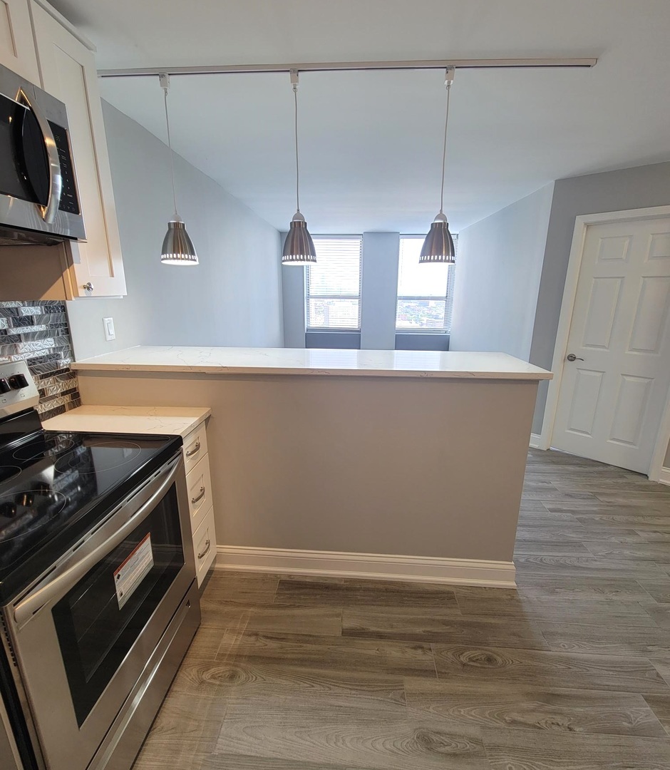 655 West Irving Park Road, Unit 2611 Chicago, IL 60613 - Photo 9 of 32 a kitchen with kitchen island a stove and a wooden floor