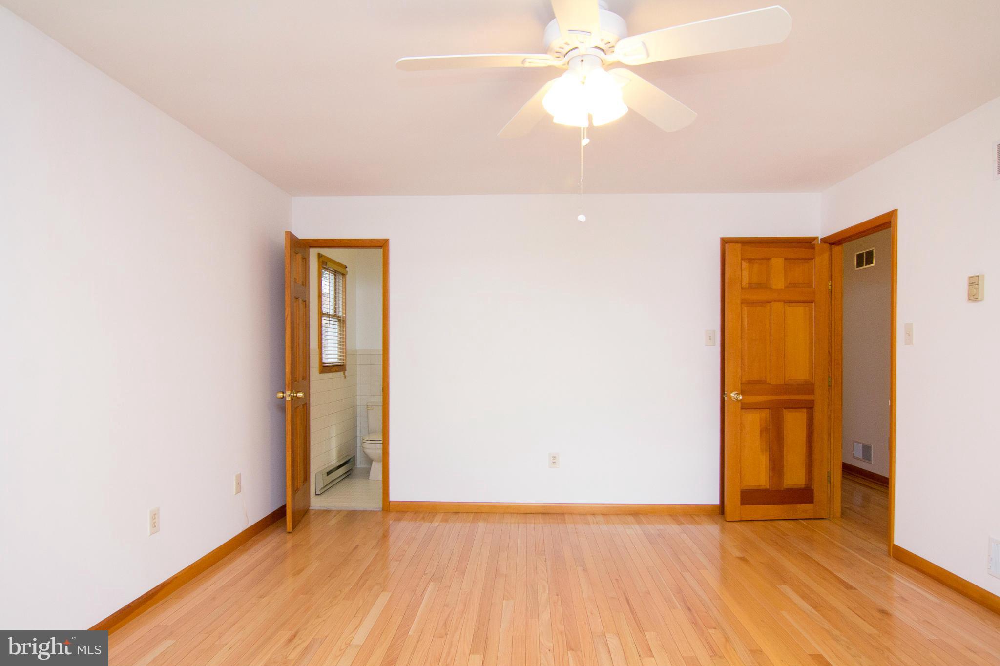 19306 Resh Mill Road Hampstead, MD 21074 - Photo 11 of 30 an empty room with wooden floor and a ceiling fan