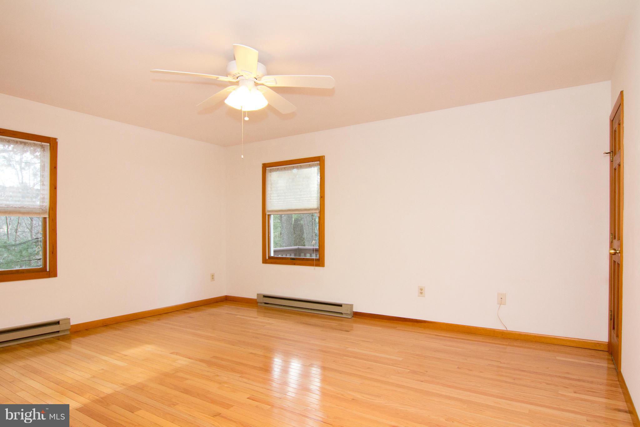 19306 Resh Mill Road Hampstead, MD 21074 - Photo 10 of 30 an empty room with wooden floor fan and windows