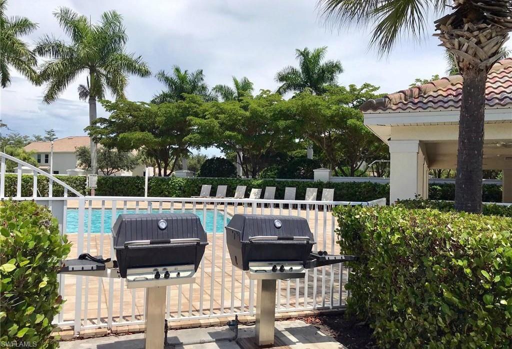 16170 Caldera Lane, Unit 37 Naples, FL 34110 - Photo 23 of 23 a picture of table and chairs with potted plants and palm trees
