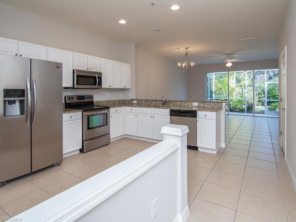 16170 Caldera Lane, Unit 37 Naples, FL 34110 - Photo 6 of 23 a kitchen with stainless steel appliances granite countertop a stove top oven a sink dishwasher a refrigerator and white cabinets with wooden floor