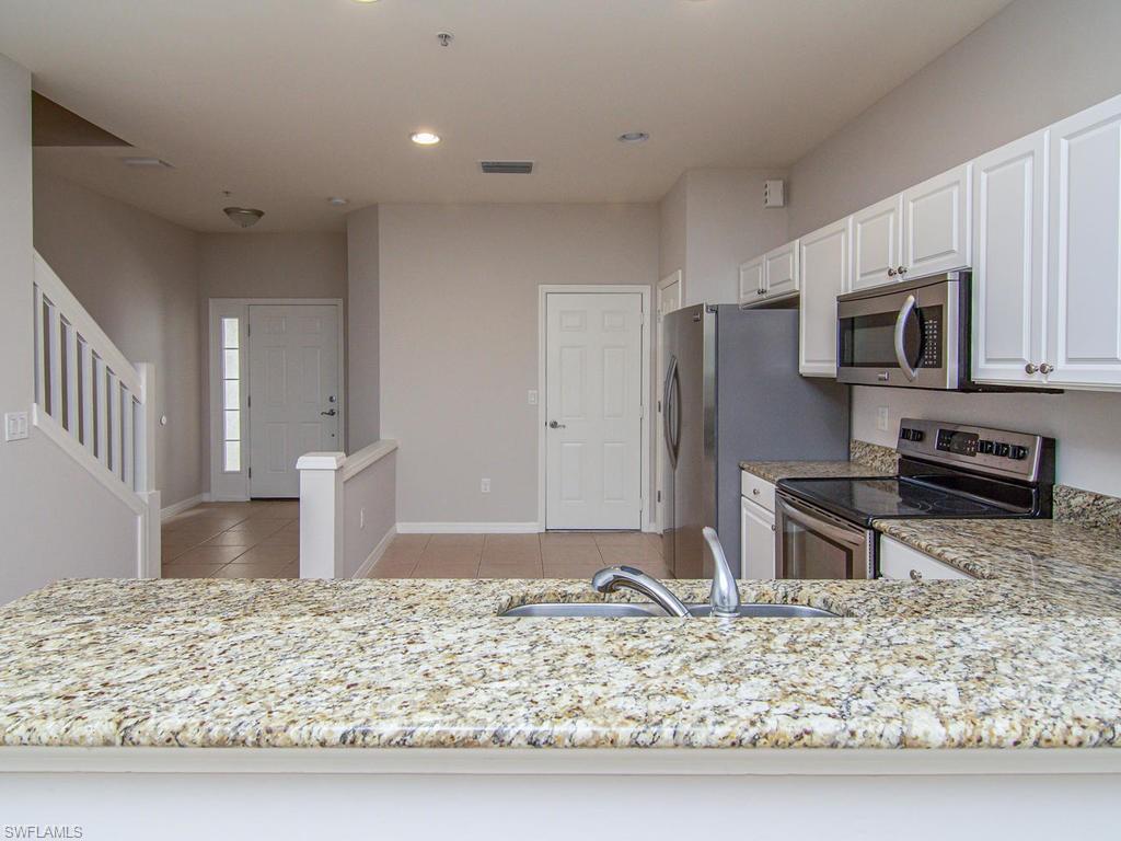 16170 Caldera Lane, Unit 37 Naples, FL 34110 - Photo 7 of 23 a kitchen with stainless steel appliances granite countertop a sink refrigerator and microwave