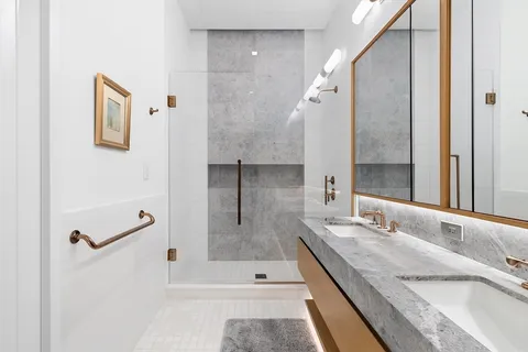a bathroom with a granite countertop sink a mirror and shower
