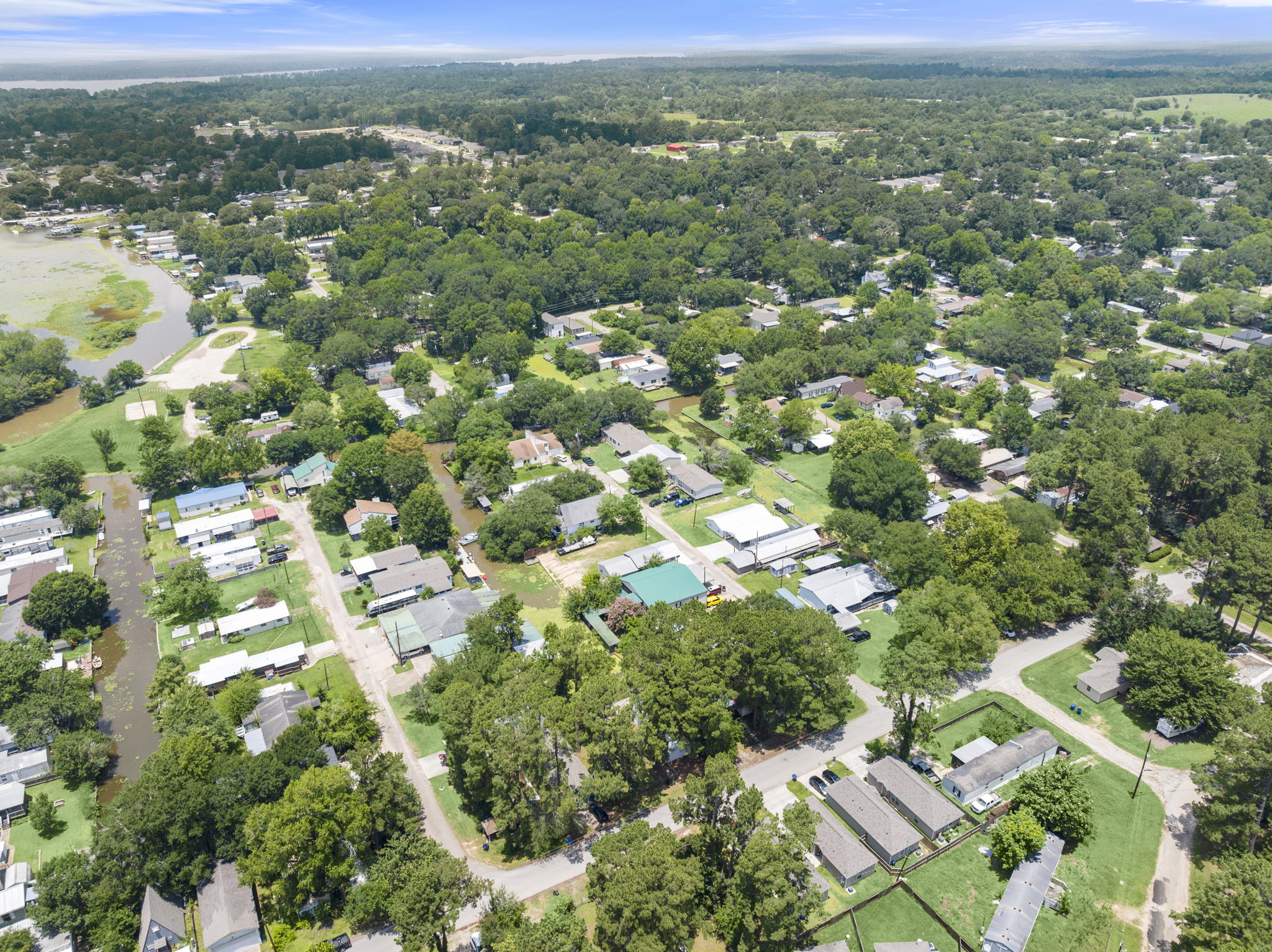 9649 Warm Spring Willis, TX 77318 - Photo 22 of 30 An aerial perspective reveals a tree-filled residential area bordering a winding river, offering a peaceful natural setting.