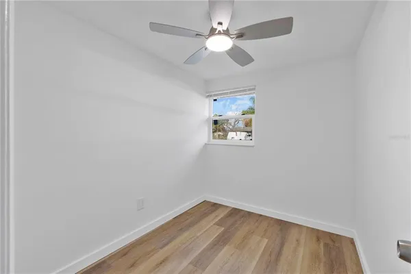 an empty room with a window and a fan