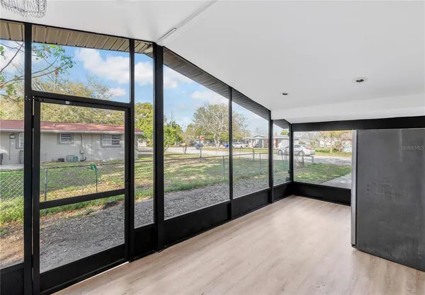 a view of an empty room with wooden floor and glass door