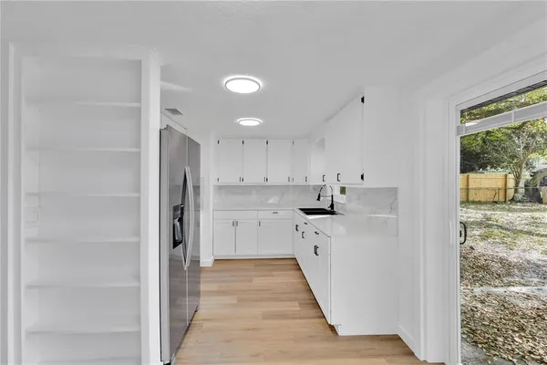 a kitchen with white cabinets and window