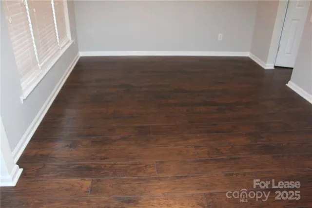a view of an empty room with wooden floor and a fireplace