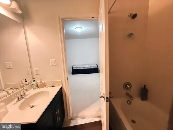 a bathroom with a tub sink vanity and mirror