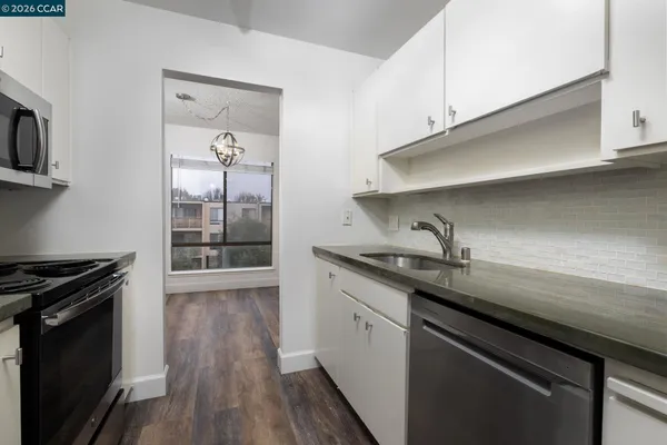 a kitchen with granite countertop a sink a stove and cabinets