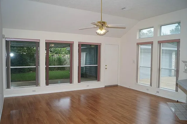 a view of an empty room with wooden floor and a window
