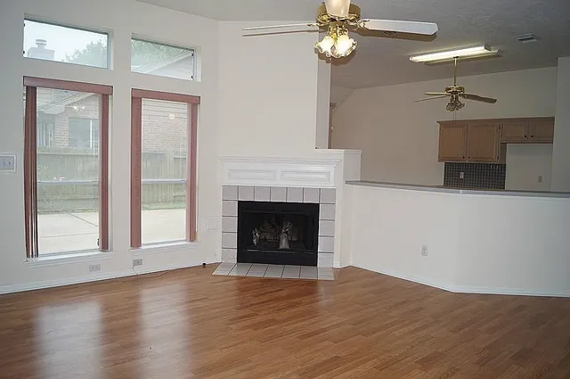 a view of an empty room with wooden floor fireplace and a window