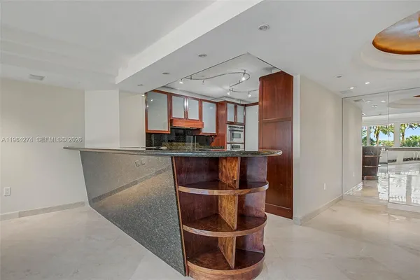 a room with stainless steel appliances kitchen island granite countertop a refrigerator a stove and a sink