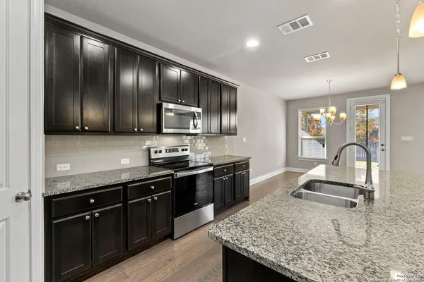 a kitchen with stainless steel appliances granite countertop sink stove refrigerator and cabinets