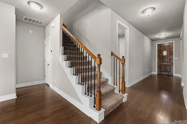 a view of a hallway with wooden floor and staircase