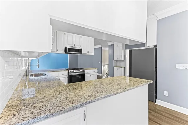 a kitchen with stainless steel appliances granite countertop a sink and a refrigerator