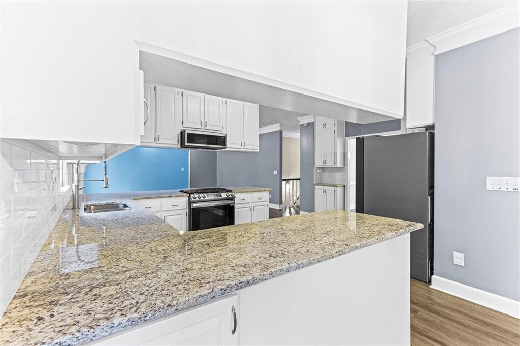 1394 Maple Drive Southwest Lilburn, GA 30047 - Photo 12 of 31 a kitchen with stainless steel appliances granite countertop a sink and a refrigerator