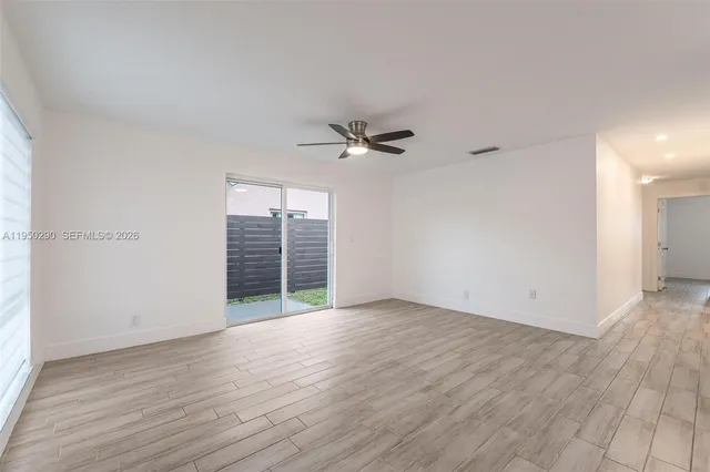an empty room with wooden floor fan and windows
