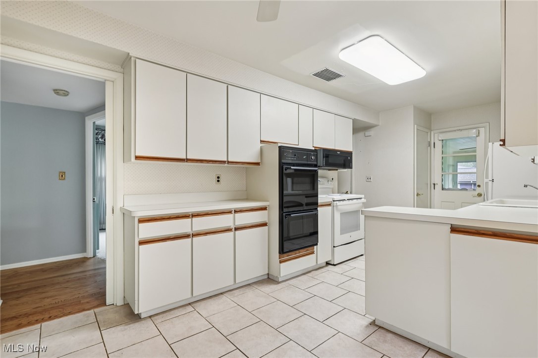 33300 South Woodland Road Cleveland, OH 44124 - Photo 22 of 50 Kitchen featuring white cabinets, light countertops, black appliances, and light tile patterned floors