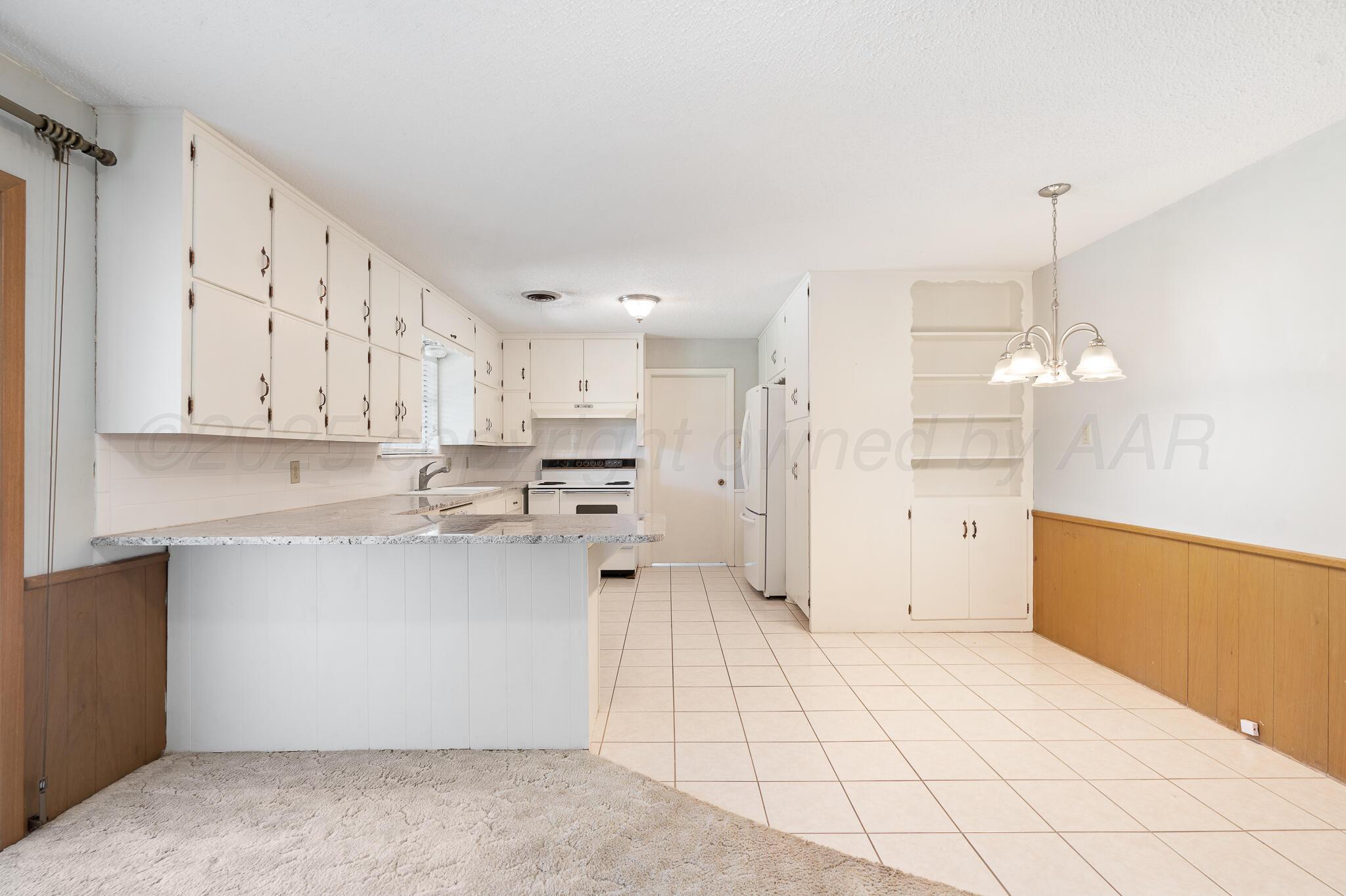 4803 Carole Lane Amarillo, TX 79110 - Photo 5 of 23 a large white kitchen with white cabinets and stainless steel appliances