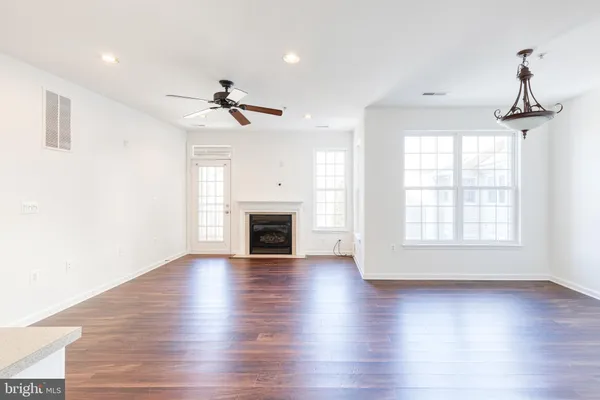 an empty room with wooden floor ceiling fan and windows